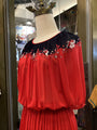 Red dress with floral embroidery on a mannequin against a reflective surface.