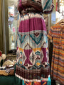 Colorful patterned dress hanging in a store with other clothing items.
