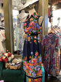 Colorful floral dress on a mannequin in a store setting with other dresses and decor.