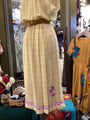 Beige dress with plaid pattern and floral details on a mannequin in a store setting.