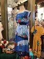 Mannequin wearing a colorful dress with sea-themed design in a store setting.
