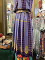Vintage-style dress with plaid pattern and gold accents in a store setting.
