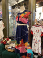 Colorful dress on a mannequin in a store setting with other clothing items.