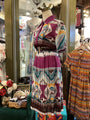 Colorful patterned dress on a mannequin in a store setting with other clothing items.