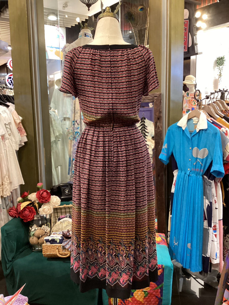 Mannequin wearing a patterned dress in a store setting with other clothing items.