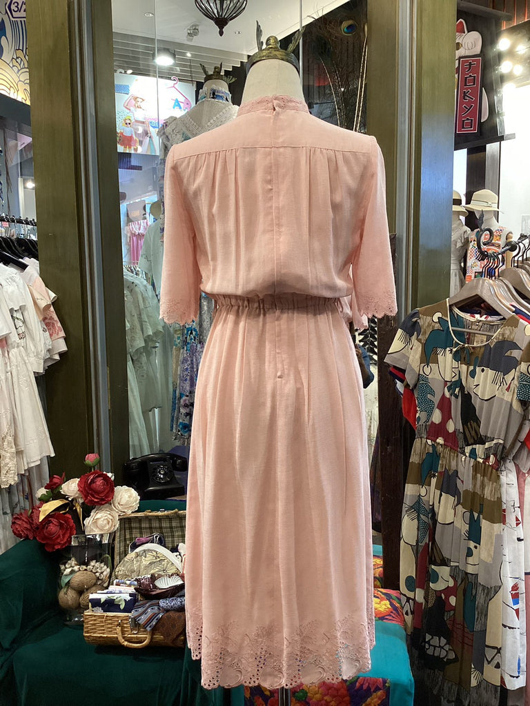 Pink dress on a mannequin in a store setting with various items in the background