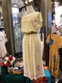 Mannequin wearing a yellow plaid dress with floral details in a store setting.