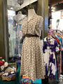 Mannequin wearing a floral dress in a clothing store with various garments in the background.