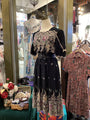 Black dress with floral embroidery on a mannequin in a store setting.