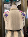 Mannequin wearing a textured garment with floral embroidery in a store setting