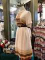 Mannequin wearing a patterned dress with a colorful top in a store setting.