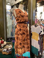 Mannequin wearing a brown dress with leaf pattern in a store setting