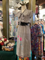 Mannequin wearing a gray dress with floral embroidery in a clothing store.