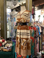 Mannequin wearing a patterned dress in a clothing store with various garments in the background.