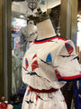 Mannequin wearing a white dress with red and blue sailboat patterns in a store setting.