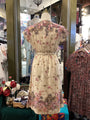 Floral dress on a mannequin in a store setting with other clothing items.