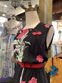 Mannequin wearing a black dress with floral embroidery in a clothing store.
