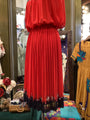 Red pleated dress on a mannequin in a store setting with colorful background