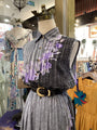 Mannequin wearing a gray dress with floral accents in a store setting