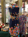 Navy dress with colorful floral embroidery on a mannequin in a store setting.