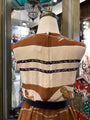 Mannequin wearing a brown and beige patterned garment with decorative elements in a store setting.