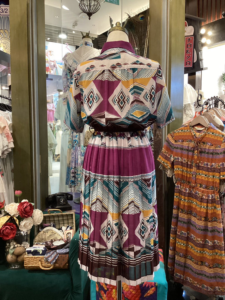 Mannequin wearing a colorful patterned dress in a store setting with other clothing items.