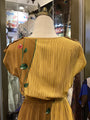 Yellow dress with floral embroidery on a mannequin in a store setting.