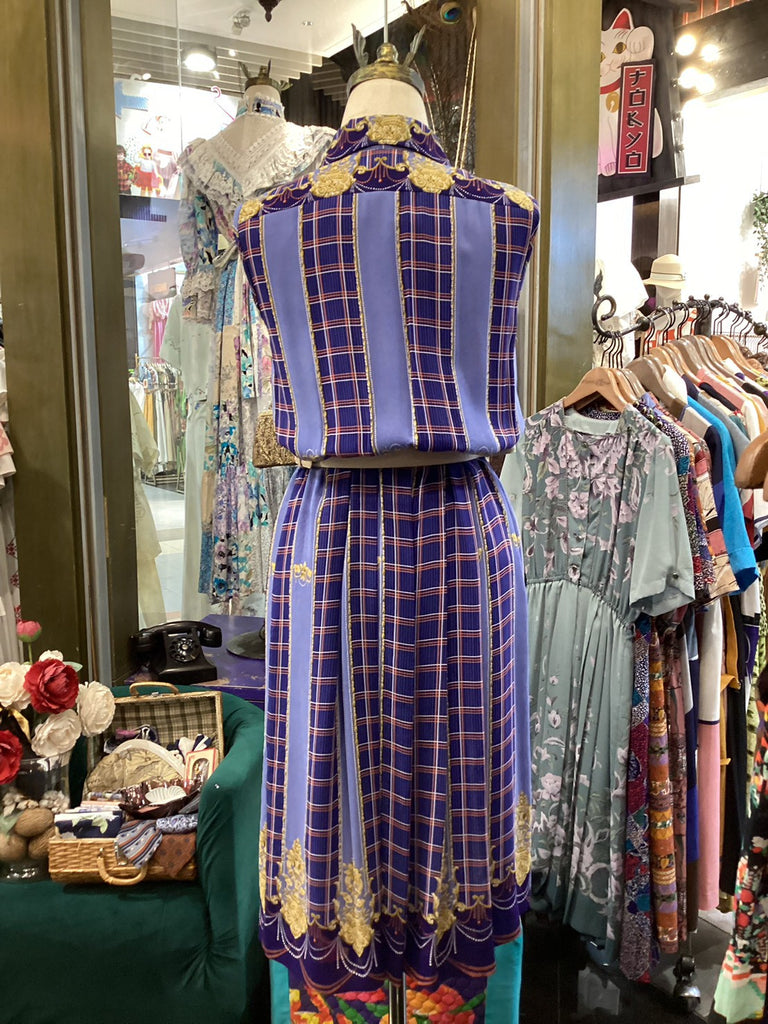 Mannequin wearing a blue plaid dress with gold accents in a store setting.