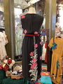 Black dress with floral embroidery on a mannequin in a store setting.