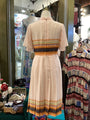 Mannequin wearing a patterned dress in a store setting with other clothing items.