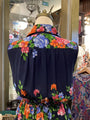 Navy blue dress with colorful floral embroidery on a mannequin in a store setting.