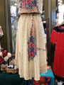 Mannequin wearing a floral top and beige skirt with red flowers in a store setting.
