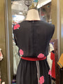 Black dress with pink floral embellishments on a mannequin in a store setting.