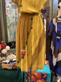 Yellow pleated dress with floral embroidery on a mannequin in a store setting.
