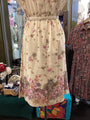 Floral dress on a mannequin in a store setting with other clothing items.