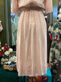 Light pink dress with lace details on a mannequin against a colorful background.
