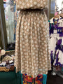 Beige dress with white floral pattern on a mannequin in a store setting.