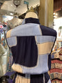 Mannequin wearing a patchwork jacket with blue, beige, and black fabric in a store setting.
