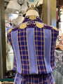 Mannequin wearing a blue and gold plaid garment with decorative elements in a store setting.