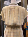 Mannequin wearing a yellow plaid dress with a blurred background
