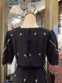 Black dress with white embroidery on a mannequin in a store setting.