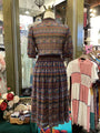 Patterned dress on a mannequin in a store setting with other clothing items.