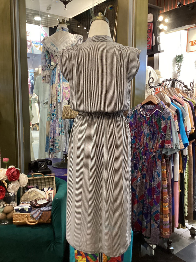 Mannequin wearing a patterned outfit in a store with racks of clothes in the background