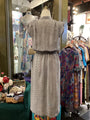 Mannequin wearing a patterned outfit in a store with racks of clothes in the background