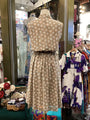 Mannequin wearing a floral dress in a store setting with other clothing items.