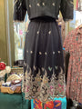 Black embroidered dress on a mannequin with a colorful background