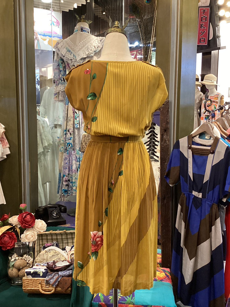Yellow dress with floral details on a mannequin in a store setting.