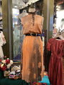Vintage-style dress on a mannequin in a store setting with other clothing items.